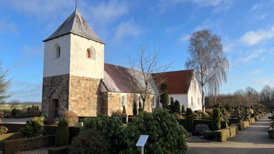 Kirke med tårn og gravhøje i forgrunden