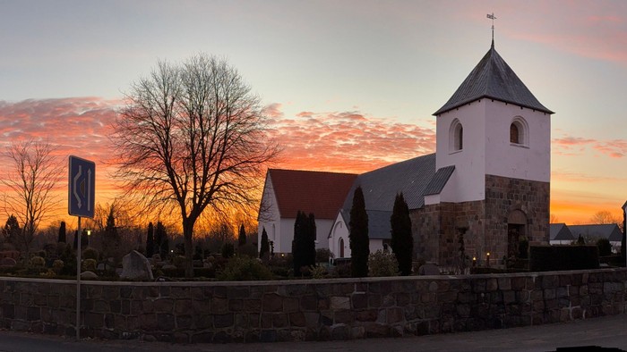En kirke og et gravsted ved solnedgang