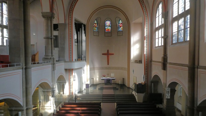 Innenraum einer Kirche mit Holzpulten und hohem Gewölbe