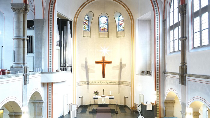 Innenraum einer Kirche mit Holzbanken und hohem Gewoelbe