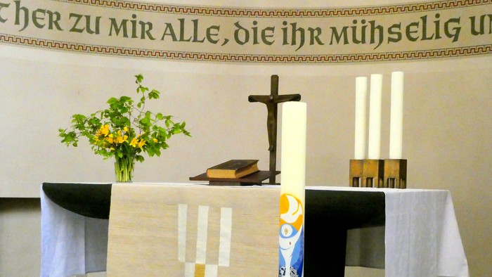Altar in Kirche mit Kreuz, Kerzen und Blumen