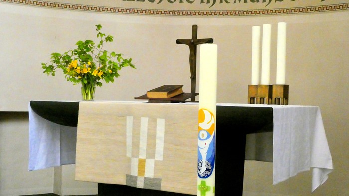 Altar in Kirche mit Kreuz, Kerzen und Blumen
