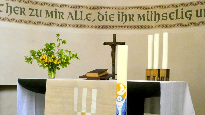 Altar in Kirche mit Kreuz, Kerzen und Blumen