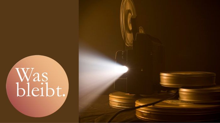 Man sieht eine Filmkamera und Filmrollen im Vordergrund.