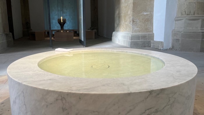 Man sieht das Taufbecken in der Christuskirche, im Hintergrund der Raum der Stille.