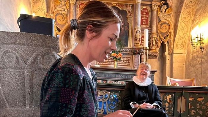 En kvinde spiller akkordeon i en kirke.