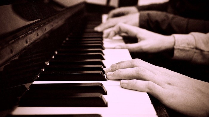 Gros plan sur des mains jouant du piano avec des mouvements de doigts précis et complexes.