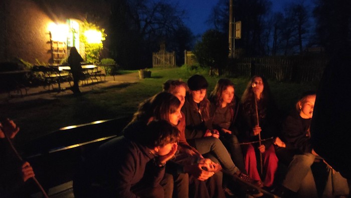 Eine Gruppe von Menschen sitzt nachts um ein Lagerfeuer.