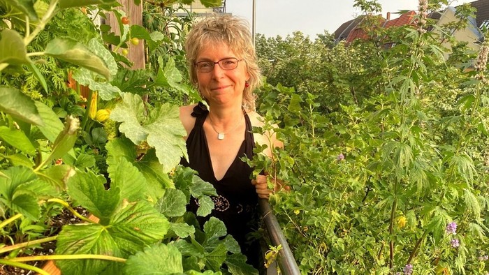 Frau im Garten mit „Bio-Balkon“-Schild und Erdbeeren