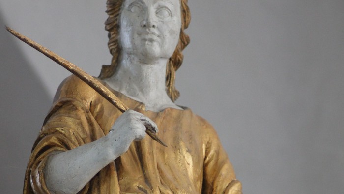 Guldstatue af kvinde med palmegren og bog.