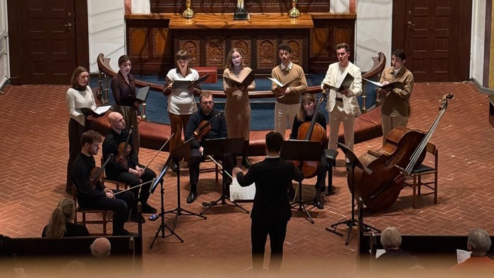 Et kammermusikensemble optræder i en historisk kirke med udsmykkede gyldne vægmalerier og et alter oplyst af stearinlys.