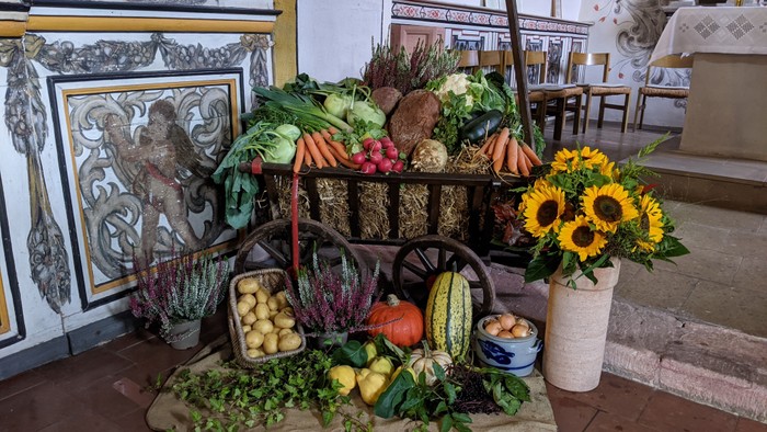 Ein Gemüsewagen mit verschiedenen frischen Produkten und einer Blumenvase in einem Raum mit Fliesenwänden