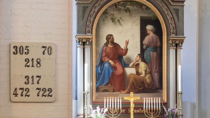 En altertavle med religiøse motiv i kirke med taltegn på veggen