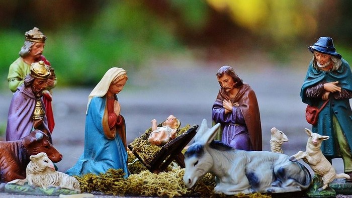 Eine Krippe mit verschiedenen Figuren, darunter Maria, Josef und das Jesuskind, umgeben von Tieren und anderen Gestalten.