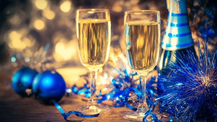 To vinglas med champagne og blå julepynt.