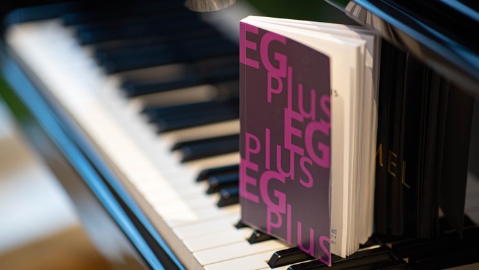 Lila Buch mit dem Titel „EG Plus“ liegt auf den Klaviertasten.