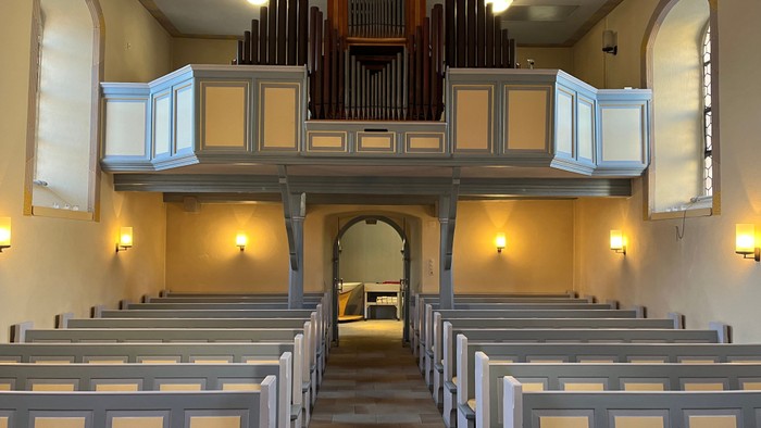 Leere Kirchenbankreihen vor einer Orgel