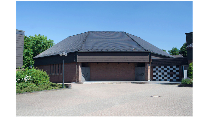 Modernes Gebäude mit geschlossenen Garagentoren, schwarz-weiß karierter Wandpaneele und klarem Himmel im Hintergrund.