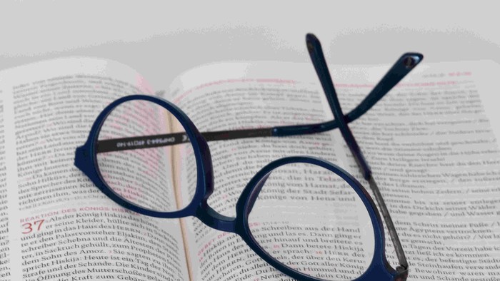 Brille und Stift auf aufgeschlagenem Buch