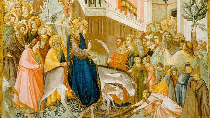 en mand med et stort følge rider på et æsel, mennesker tager i mod ham