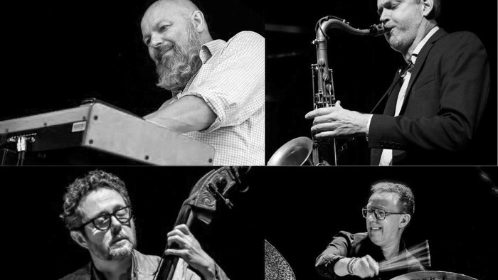 Et kvartet musikere, der spiller jazzinstrumenter på scenen under en liveoptræden.