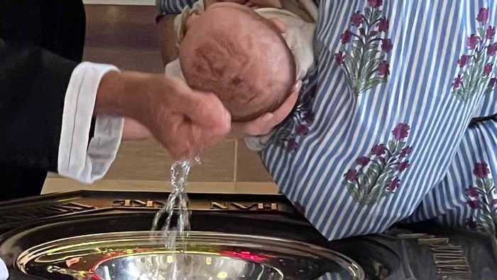 Barnedåb hvor præst fører vand til dåbsbarnets hoved 