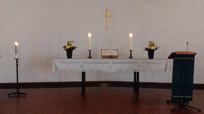 Ein Altar mit Kerzen, Blumen und Kreuz in einem Raum