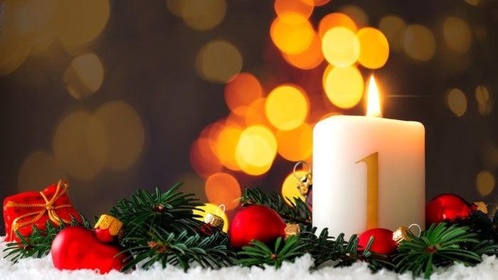 Weihnachtliche Dekoration mit brennender Kerze und Christbaumschmuck