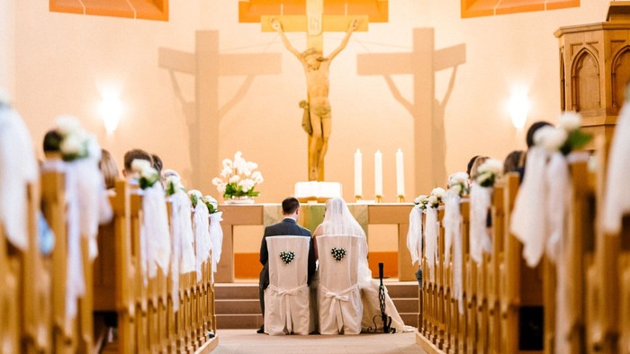 Ein Brautpaar bei der Trauung in einer Kirche vor dem Altar.
