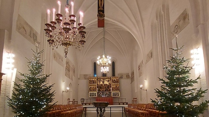 Indre del af kirke med julestænder og lys.