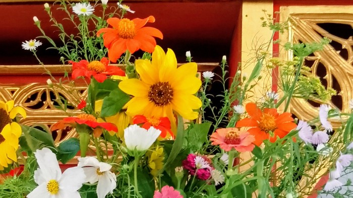 Auf dem Bild ist ein Herbstblumenstrauß vor einem Altar zu sehen.