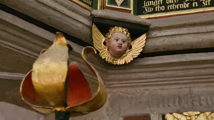 Engelsfigur mit goldenem Heiligenschein und Federkleid an einer verzierten Wand