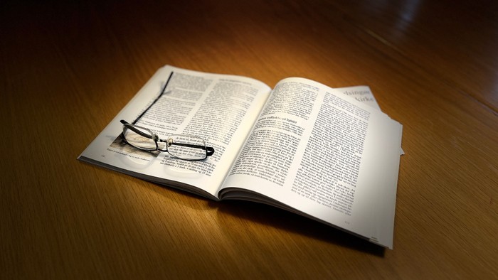 Illustration: Briller på en åben bog på et bord.