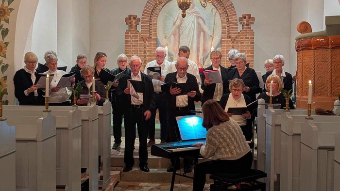 En kor sang i kirke med præst og musikere