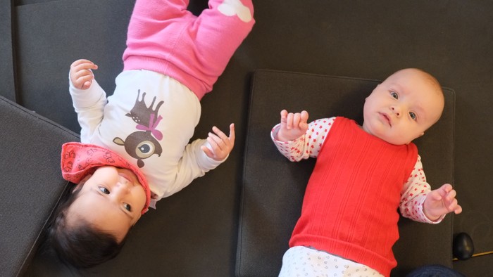 To børn ligger på magen på gulvmatte