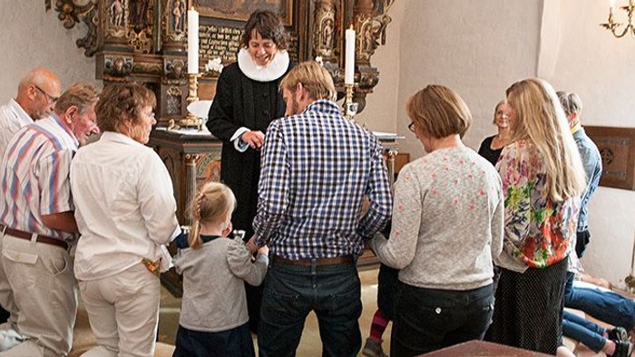 En gruppe af mennesker samles i en kirke for at se et kunststykke.