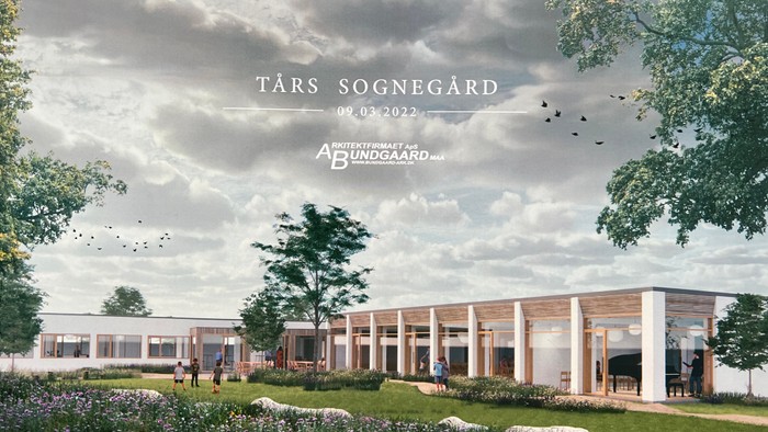 Moderne bygning med store vinduer og omgivende grønne områder under en overskyet himmel.