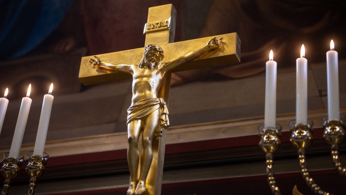 Guld crucifix med lysende lysstake og gyldne kæder.