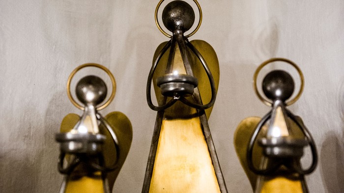 Tre metalliske figurer med gule klæder og sølv hoder.