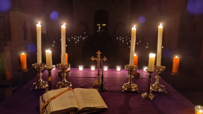 Kirchenaltar mit brennenden Kerzen und aufgeschlagenem Buch
