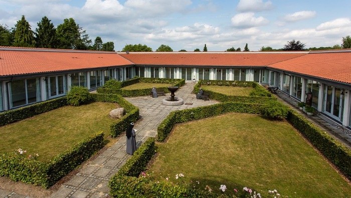 En smuk have med kliprede hegn og røde tagtegnende på en stor bygning