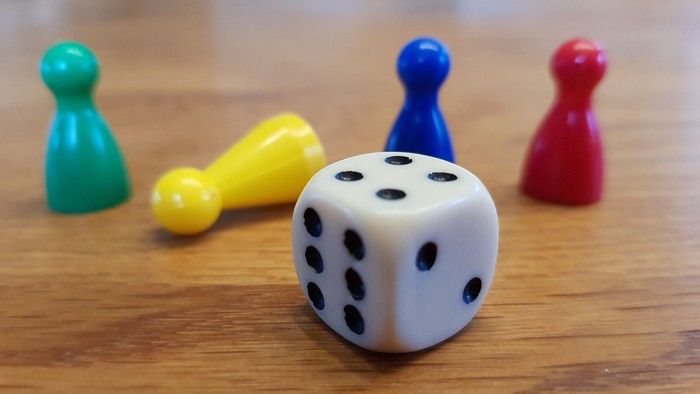 Ein Würfel mit 4 bunten Brettspielfiguren