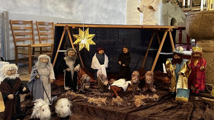 En juleoppsætning med several figurer og dyr omkring en krippe.