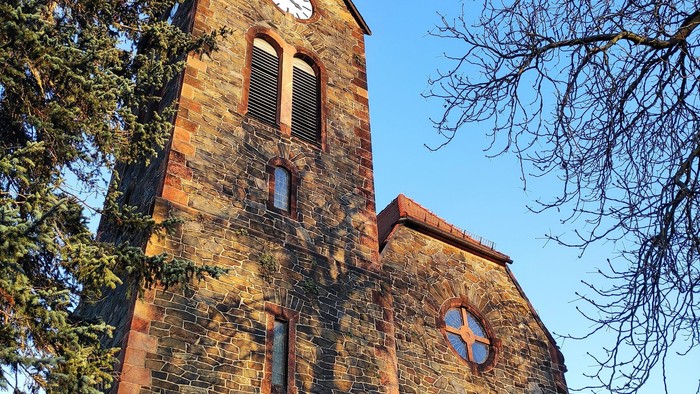 Gotische Kirche mit hohem Turm und Uhr.