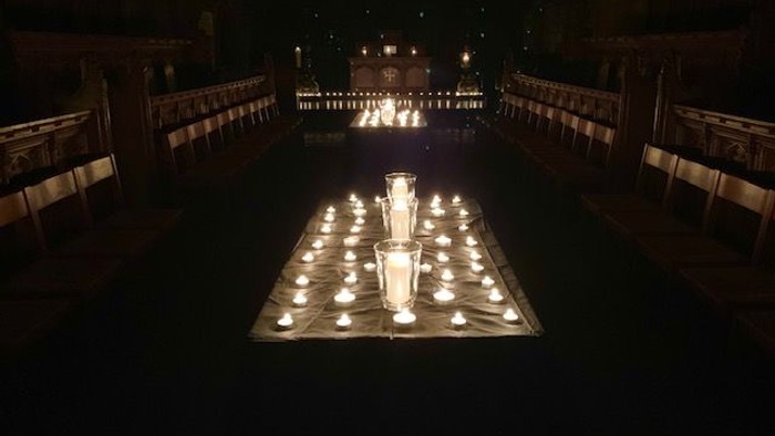 Candles lit in a dark room with rows of chairs