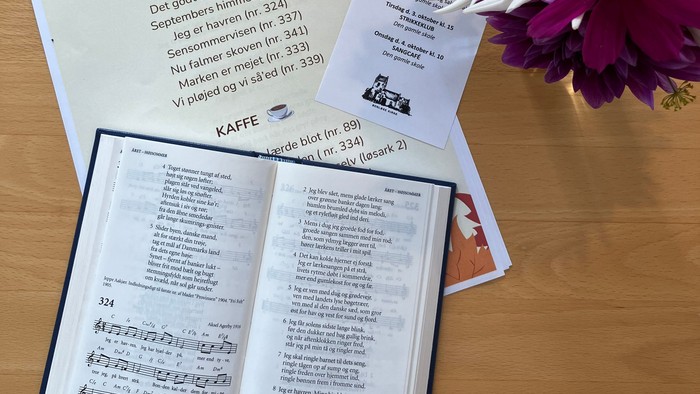 Program for Sangcafé den 13. september med blomsterdekor.