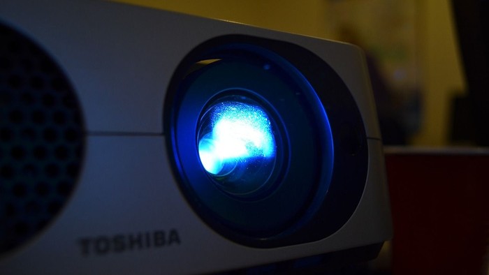 Ein Toshiba Projektor mit leuchtender Blaulampe.