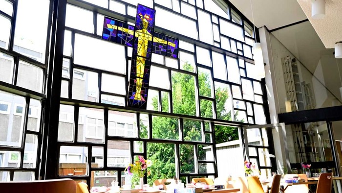 Ein Kirchenfenster mit einem großen Kreuz und Holzbänken im Vordergrund