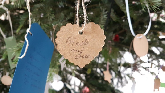 Ein Weihnachtsbaum mit selbstgebastelten Schmuckstücken, darunter ein Herz mit der Aufschrift