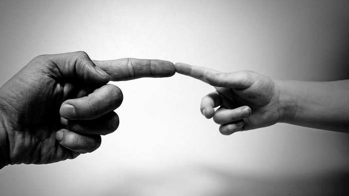 To hands træffer hinanden med fingrene.